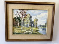 Frontal photo of framed autumn riverscape oil painting on board, showing detail and color.