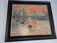 Framed art print on wall showing the full piece including black wood frame with gold trim.