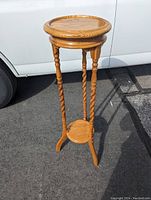Full view of the oak wood plant stand showing top round surface, three rope twisted legs, and smaller bottom round shelf.