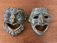 Front view of both bronze masks showing detailed facial features and patina.