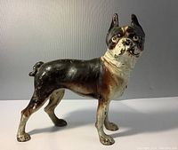 Left side view of the antique cast iron Boston Terrier doorstop with detailed facial features and moderate paint loss.