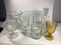 Front view of the entire set showing various sizes and shapes of pressed glass items including goblets, compotes, sugar bowl, bread tray, and candle holder.