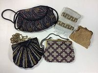 Top view of five evening bags laid flat showing variety in beadwork, fabric, and metal mesh.