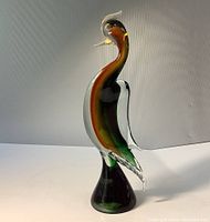 Full side view of the vibrant Murano glass bird figure showing its layered colors and clear glass wing.