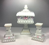 Front view of three piece set, candy dish centered with two candle holders on either side showing hand painted floral pattern and gold accents.