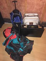 Photo of five assorted bags including duffel bags, rolling backpack, hard-shell travel case, and briefcase, showing condition and details.