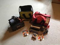 Photo showing various items in the lot including battery charger, bags, batteries, and flashlights arranged on floor.