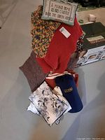 Photo showing assortment of pillows and blankets on floor, including decorative pillows and handmade blankets.