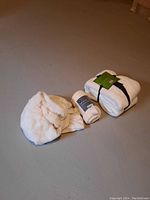 Photo showing the white plush fleece blanket partially unfolded and two more blankets fully folded with straps and tags visible.