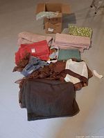 Overview of assorted blankets and fabric pieces in various folded states and colors.