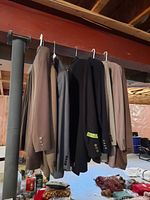 Photo of blazer jackets hanging on hangers on a horizontal pipe, showing multiple colors: beige, gray, black, and brown tones.