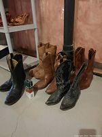 Full view of all 5 pairs of cowboy boots arranged in a row showing different colors and styles.