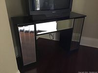 Front view of the mirrored dresser/desk with TV on top, showing mirrored side panels and central mirrored panel.
