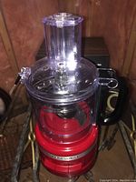 Front view of the red KitchenAid food processor showing base, clear bowl, lid and feed chute.