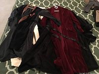 Six housecoats spread on floor, showing variety of dark colors and fabrics including velour and fleece.