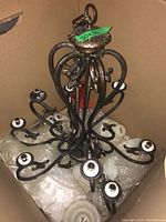 Photo showing full view of metal chandelier with multiple arms for bulbs, packed in cardboard box with bubble wrap.