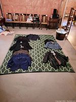 Green and white patterned outdoor carpet on concrete floor with clothing items displayed on top for size reference.