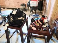 Photo showing three ladies hats stacked on a stool and four pairs of decorative shoes arranged on a table nearby.
