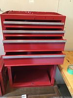 Front view of red Waterloo tool box with drawers open and bottom shelf visible showing wear and missing top cover.