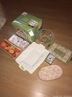 Lot of assorted serving trays and glass bowl with boxed 3-tier buffet server on floor.