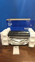 Brother 760 toner cartridge in packaging with protective styrofoam, showing exterior box with '760 2PK' label.