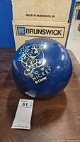 Navy blue Brunswick bowling ball front view featuring Mickey Mouse graphic and original box behind.