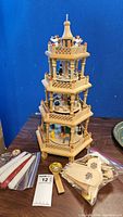 Full height view of the four-tier wooden nativity carousel with accompanying candle and fan blade accessories around the base.