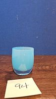 Front view of the blue Glassybaby candle votive showing smooth rounded edges and thick base, on blue background with lot number.