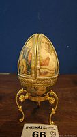 Front view of the decorative egg showing painted religious figures and pearl embellishment