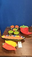 Full view of all colorful ceramic serving dishes including chili pepper shaped bowls and tray