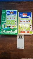 Full view of the hand-held MVP Baseball electronic game next to the original box on a wooden surface. The game face shows a baseball field with labeled action buttons.