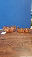 Side view of pink depression glass relish tray and serving bowl on wood surface, blue backdrop