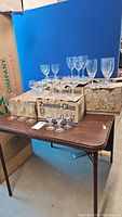Wide shot of multiple glassware types on table with original boxes; includes stemware of various heights and shapes.