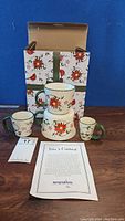 Four ceramic cups in various sizes with bird and floral decorative pattern, original box with similar design and informational paper about the pattern.