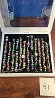 Full display case open showing 12 bracelets labeled Jan–Dec
