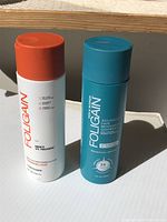 Photo showing the white and orange conditioner bottle and the blue shampoo bottle together on a white surface with natural lighting.