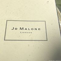 Close-up of Jo Malone London logo on fabric box cover.