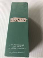 Front view of sealed green box labeled La Mer The Resurfacing Treatment Lotion Exfoliante 3.4 fl oz / 100 ml.