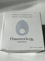 Photo showing front of sealed white box of Omorovicza Thermal Cleansing Balm, 50ml size, with branding and product name.