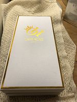 Closed white and gold-trimmed box marked Oryn House in gold lettering with crown logo.