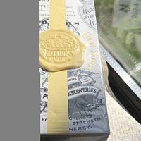 Front and side of sealed box showing silver design, yellow ribbon and wax seal