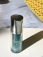 Full view of the bottle standing upright on white surface showing silver cap and teal-colored hydro gel inside.