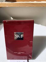 Front of the box showing SK-II logo, product name 'Facial Treatment Mask'. Box is sealed but slightly damaged with small dents and creases.