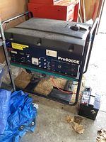 Front view of Onan Pro6000E generator on steel frame with control panel and attached battery