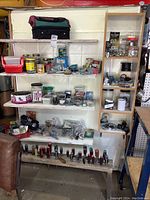 Overview of shelves displaying various screws, nails, hardware in containers, and tools with a soft tool case on top shelf.