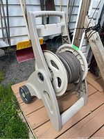 Suncast plastic mobile hose caddy with grey coiled garden hose stored on reel, showing general appearance and condition.