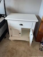 Nightstand showing top drawer slightly open and left cabinet door open, revealing interior shelving.