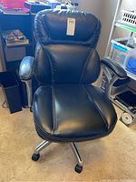 Front view of black office chair showing padded backrest with white stitching, padded seat and armrests, caster wheels on metal base.