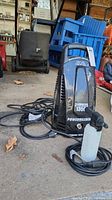 Full view of the Powerwasher pressure washer unit model PW1350 with attached hose and cord on concrete floor.