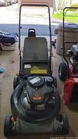 Front view of Remington lawn mower with visible 21 inch cutting deck, black plastic grass catcher bag, and handle bar